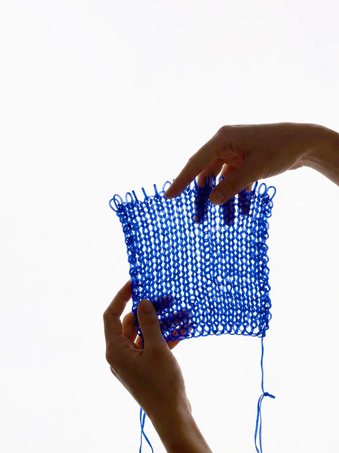 Hands holding a square of cobalt-blue knitted bioyarn — Mother of Pearl